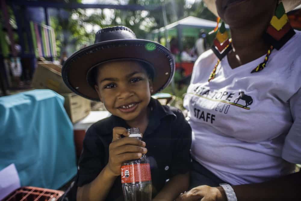 Children dressed in colorful Rasta clothing, watching the horse parade at the Rasta Tope