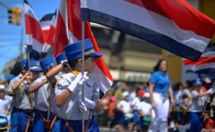 Children carry Costa Rican flags during Alajuela's Juan Santamaría Day parade in 2014.