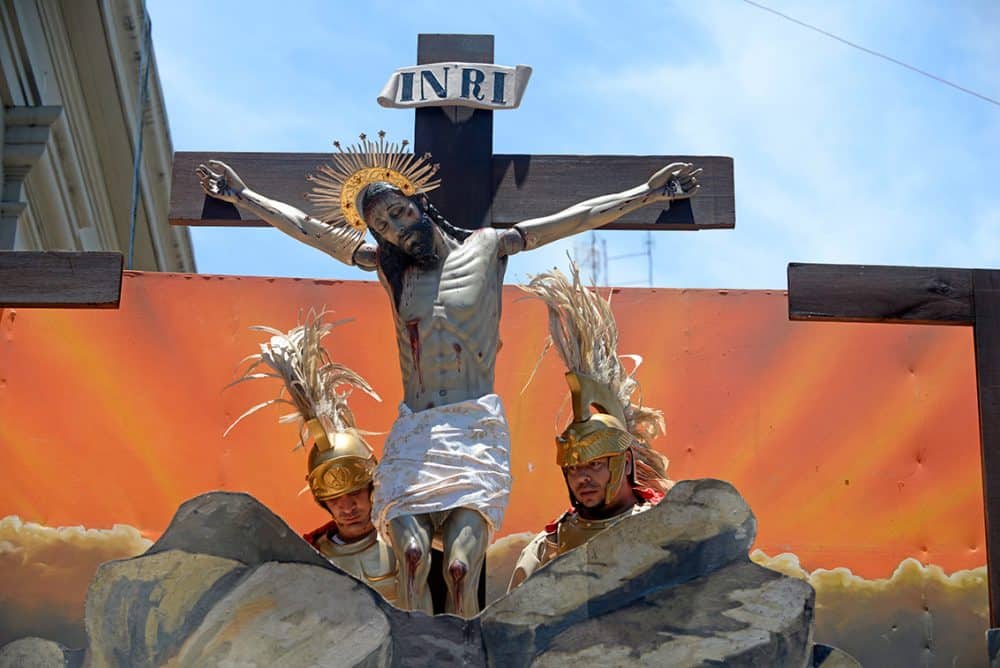 Close‑up of a wooden statue of Christ on the cross being carried by confradía members in Costa Rica’s capital