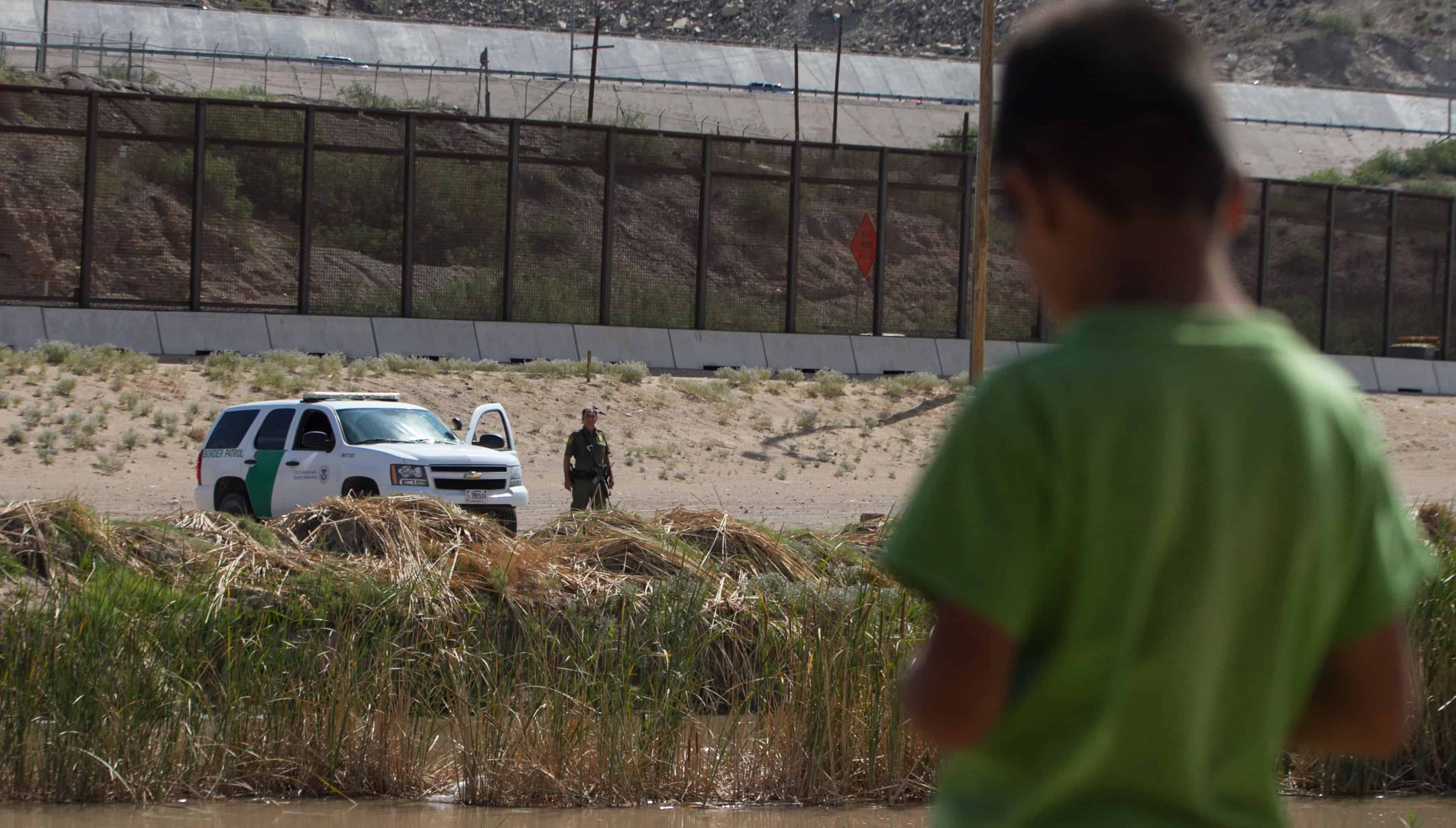 A Mexican boy looks at a member of the U.S. Border Patrol standing guard on the border between El Paso in the United States and Ciudad Juárez in Mexico, on July 22, 2014.