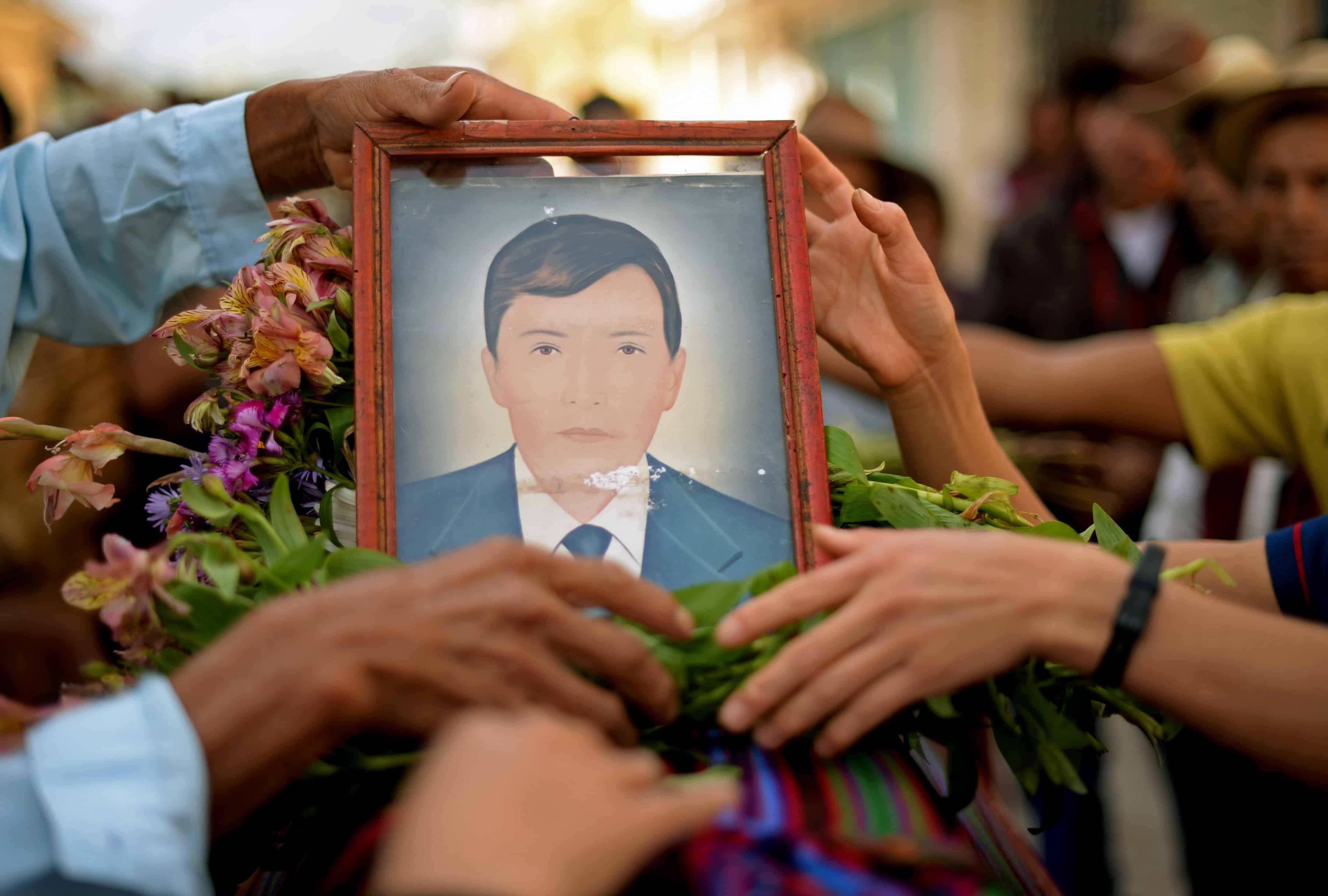 Mayan Ixil people hold a portrait of Miguel Marcos