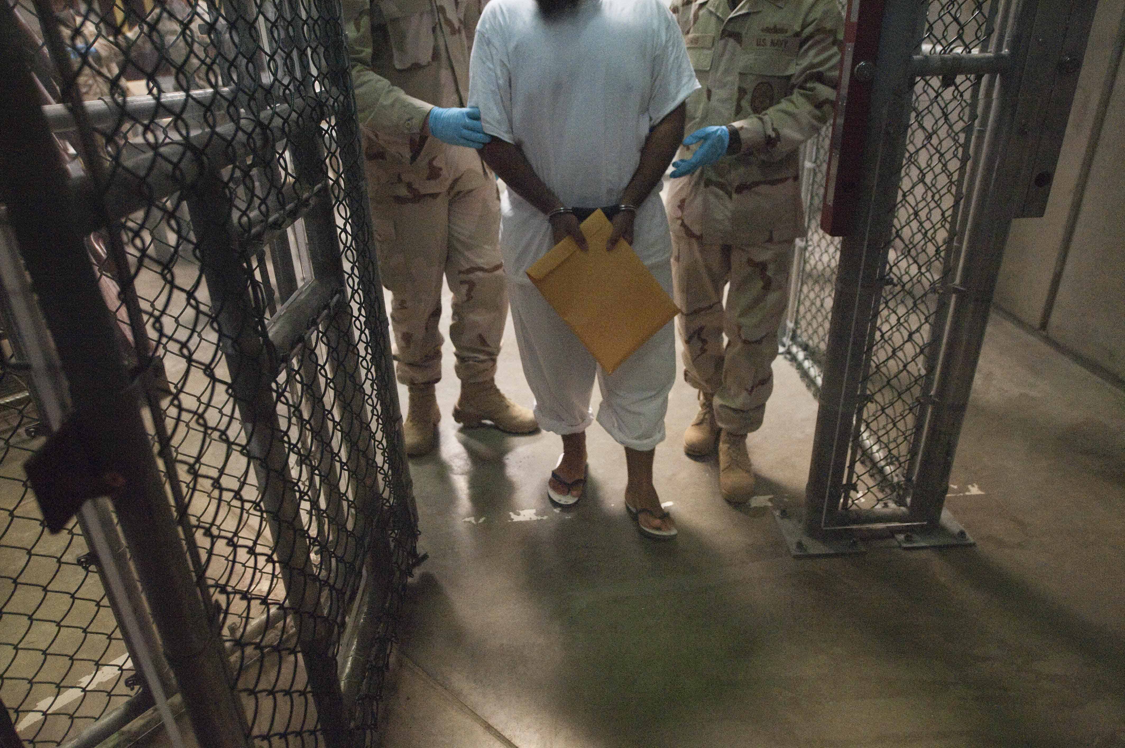 A March 30, 2010 file photo shows U.S. military guards as they move a detainee inside Camp VI at Guantanamo Bay, Cuba.