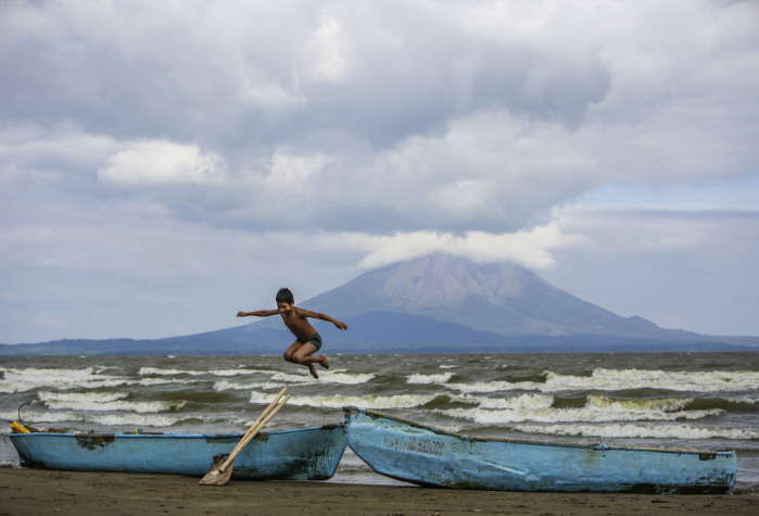 A young boy plays near two fishing boats along the shore of Lake Cocibolca in Rivas, Nicaragua.