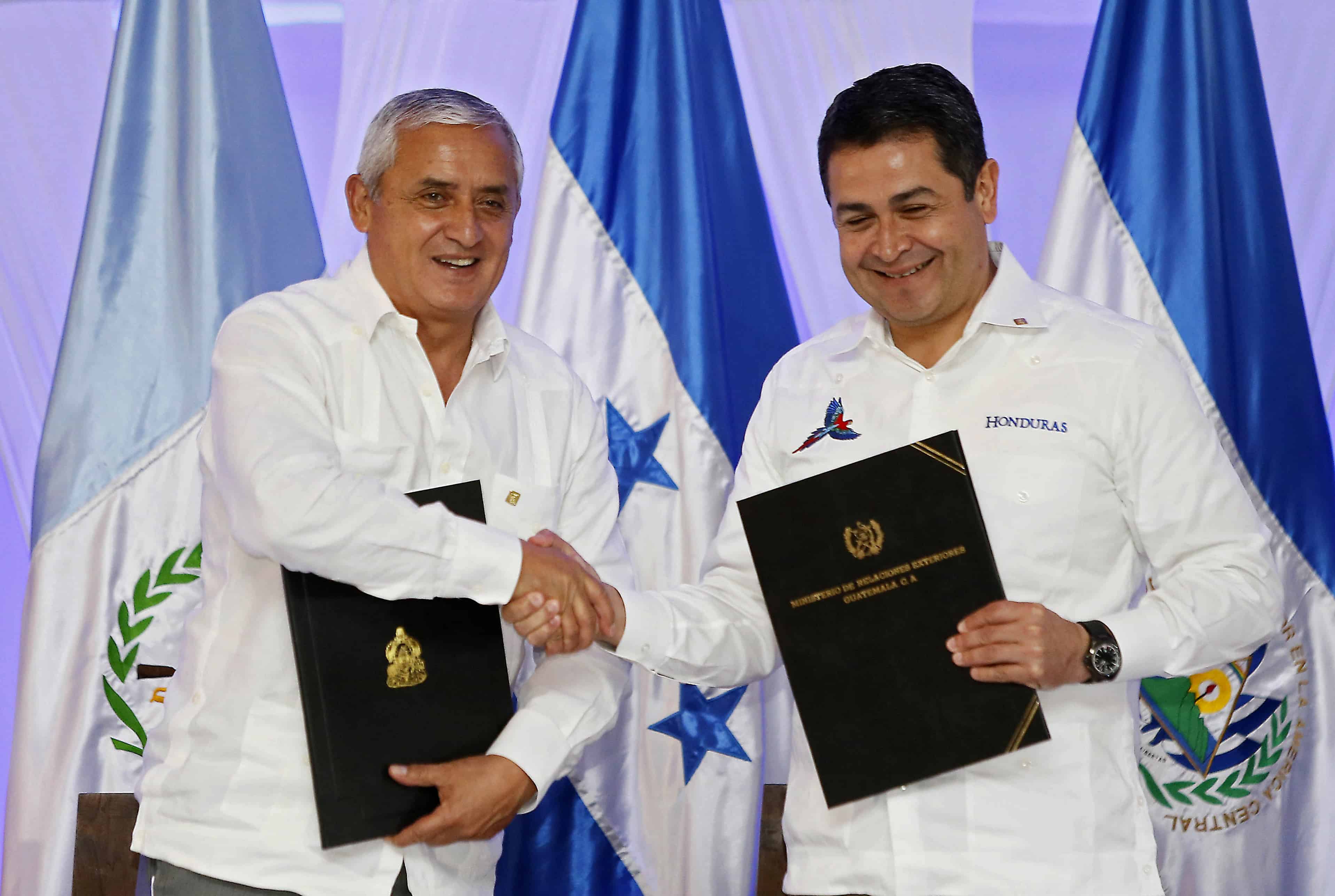 Honduran President Juan Orlando Hernandez (R) and his Guatemalan counterpart Otto Perez Molina as they shake hands after signing an intention letter of customs union during the first meeting of the Alliance for Prosperity of the North Triangle in Tela, Feb. 26, 2015.