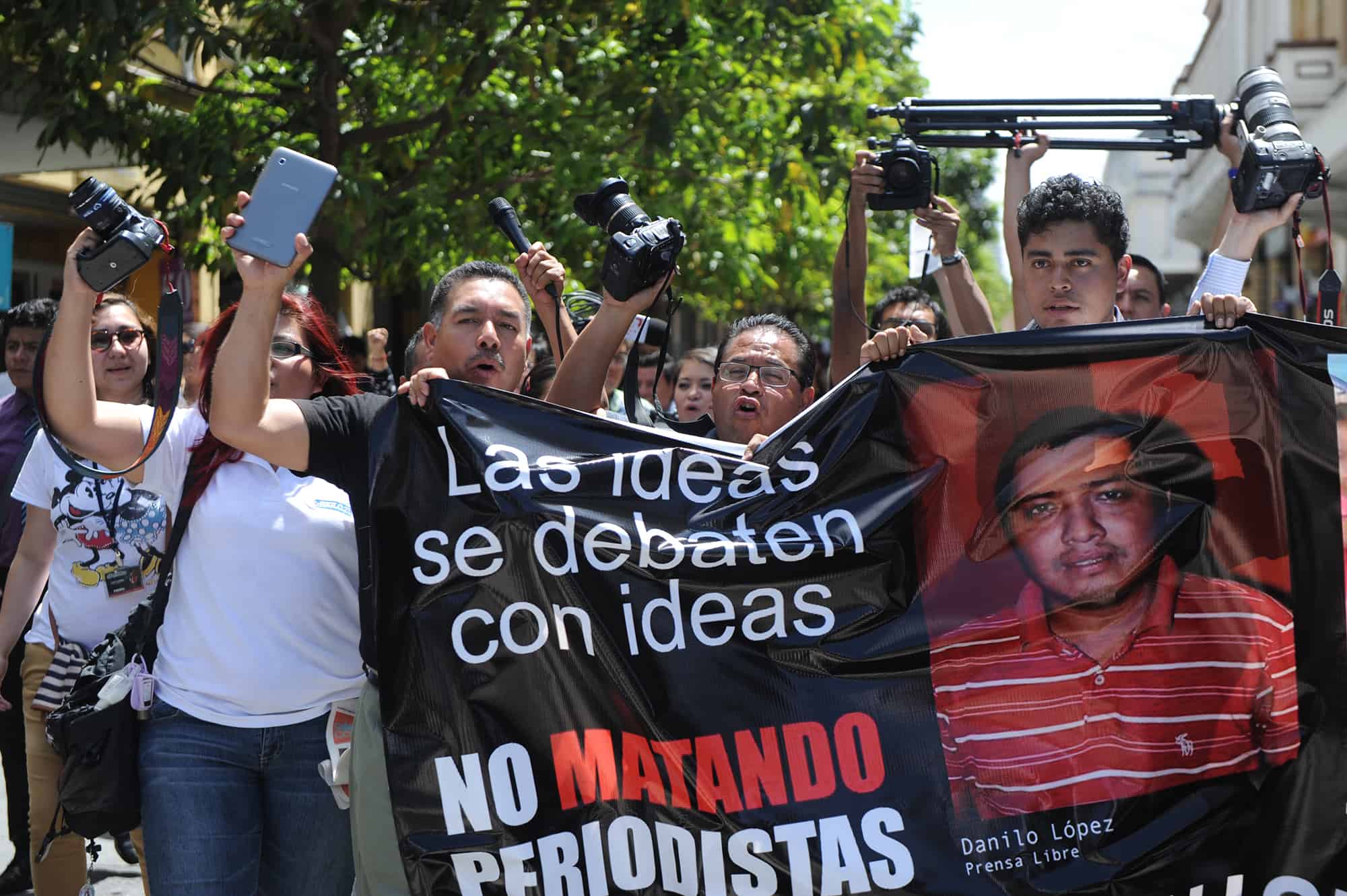 Guatemalan journalists carry a banner with the photos of two journalists killed on March 10 in an attack. Guatemala City, March 11, 2015.