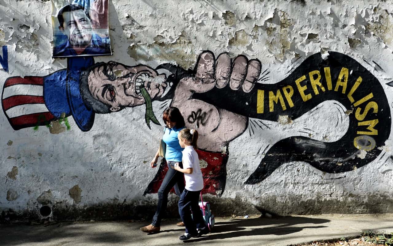 A woman and girl walk in front of a graffiti of Uncle Sam in Caracas on March 11, 2015.