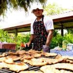 A cook overseas a grill full of steaks. All food served at the picnic was produced on the EARTH University campus.