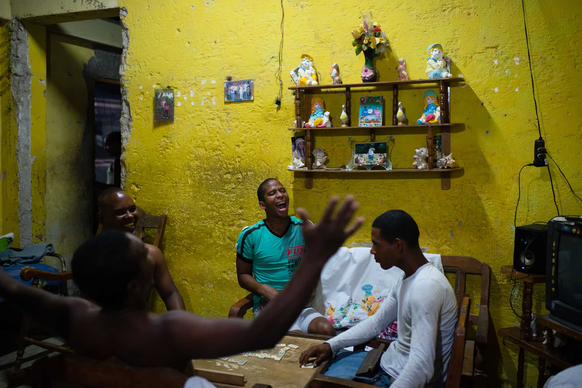 In the poor neighborhood of Juruquey in Camaguey, Cuba, shown on Feb. 3, 2015, Yasmany Garcia, 26, in green, screams with excitement at the end of a round of dominos with his friends at his home. Camaguey is Cuba's third largest city with more than 321,000 residents.