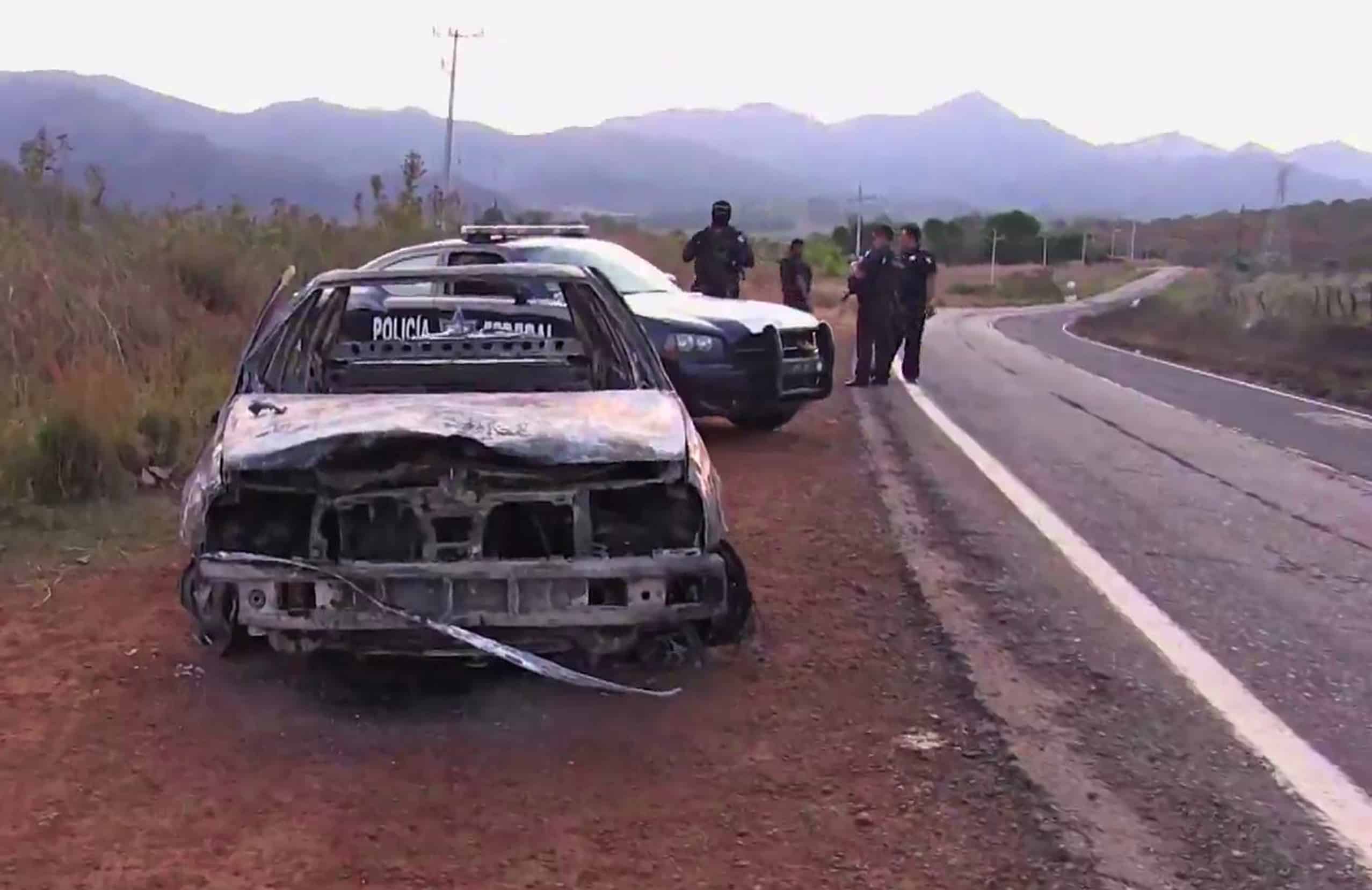 Grab taken from a video of policemen inspecting a burnt police vehicle on April 7, 2015 on a Jalisco state road, Mexico, where at least 15 police officers were killed in an ambush carried out by a gang called 