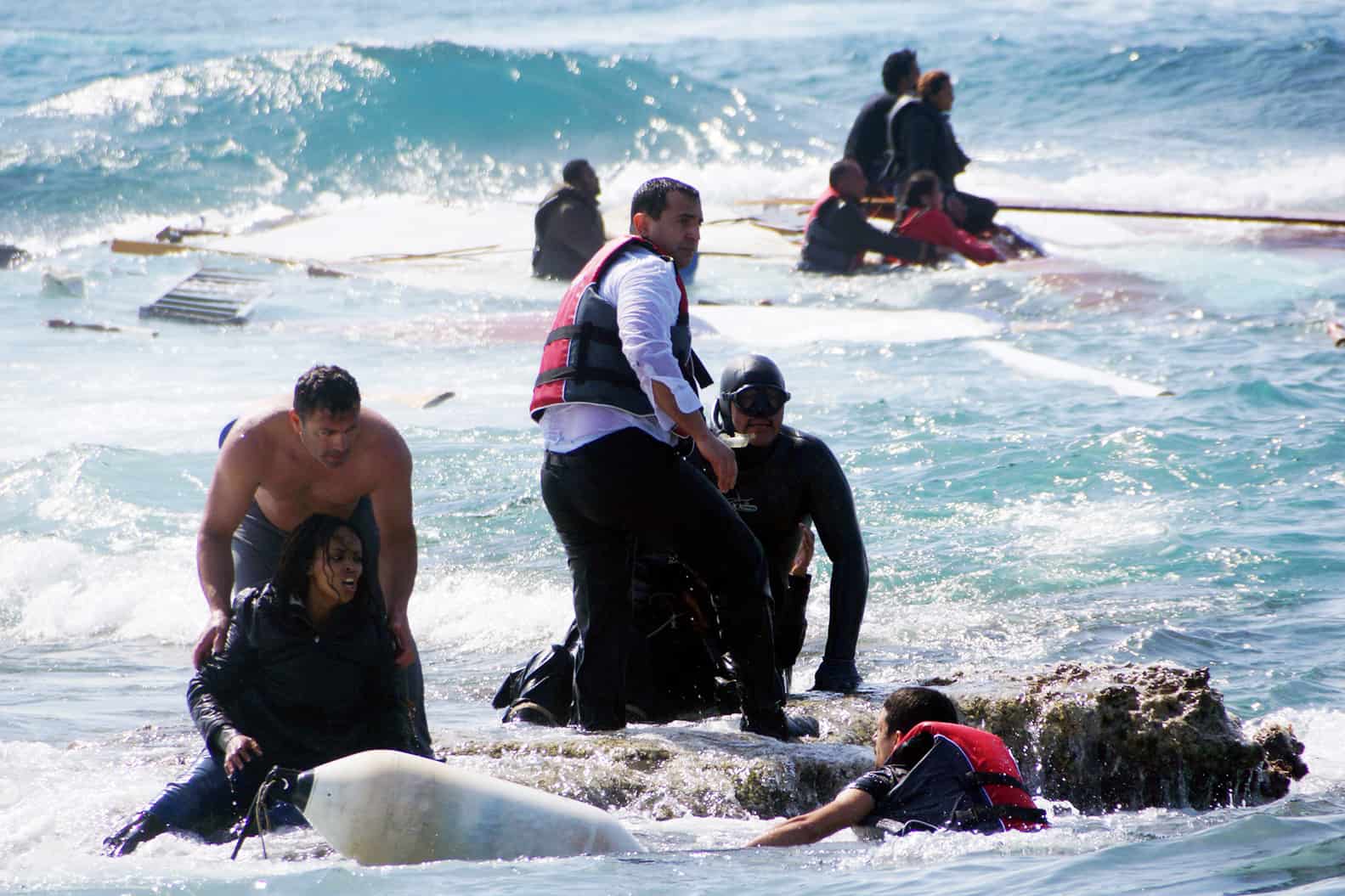 Local residents and rescue workers help a migrant woman after a boat carrying migrants sank off the island of Rhodes, southeastern Greece, on April 20, 2015.