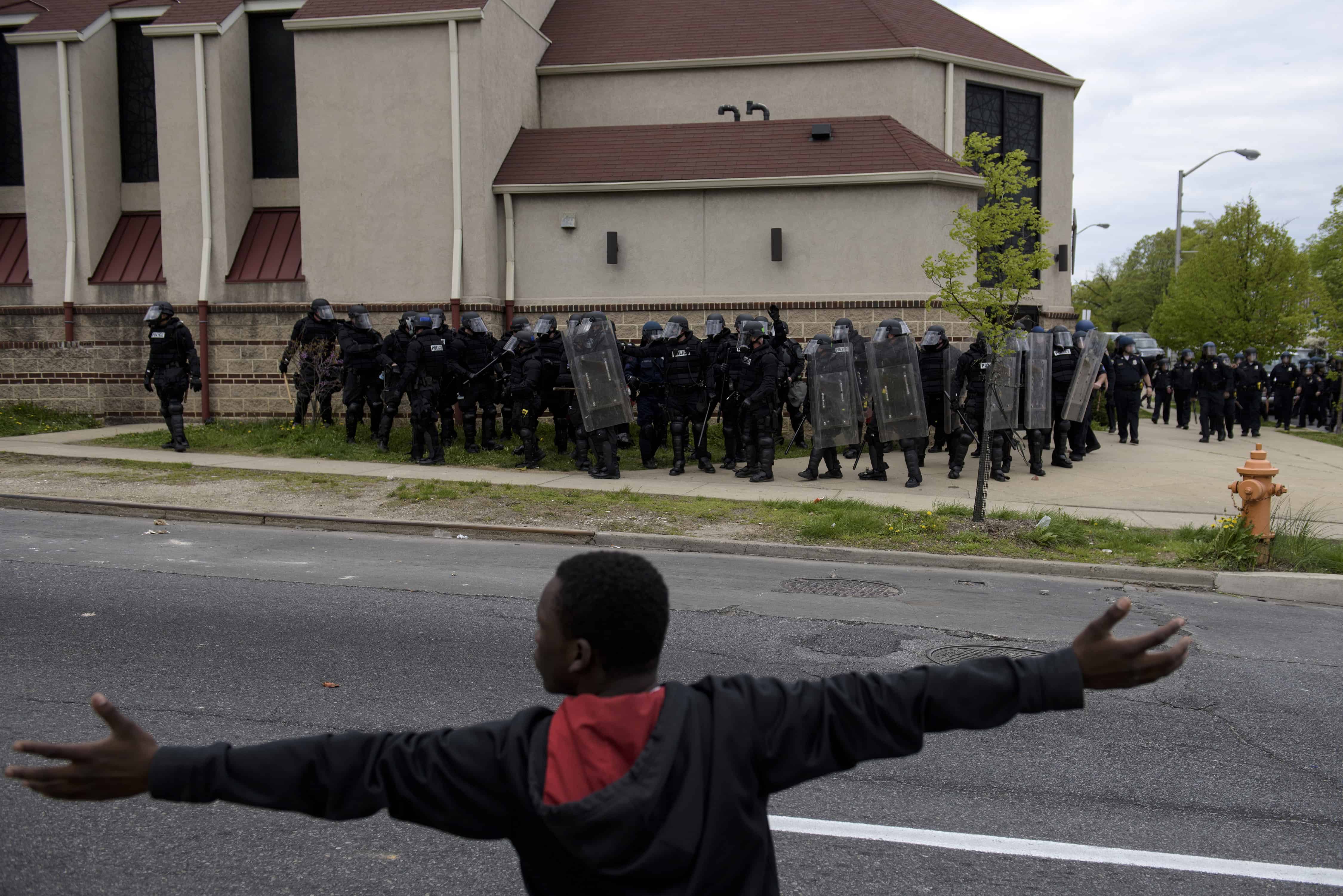 A protester gestures before riot police on April 27, 2015 in Baltimore, Maryland.