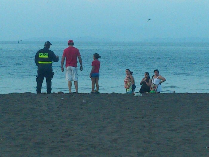 A police officer stands watch on a beach.