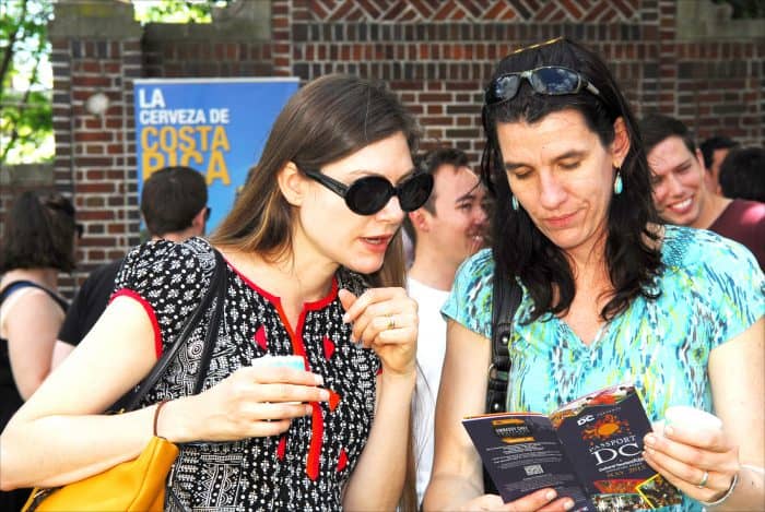 From left, Shelley McGinnis and Jessica Sahota, both visiting from California, consult a guide to Passport DC festivities Saturday, May 2, while relaxing at the Embassy of Costa Rica.