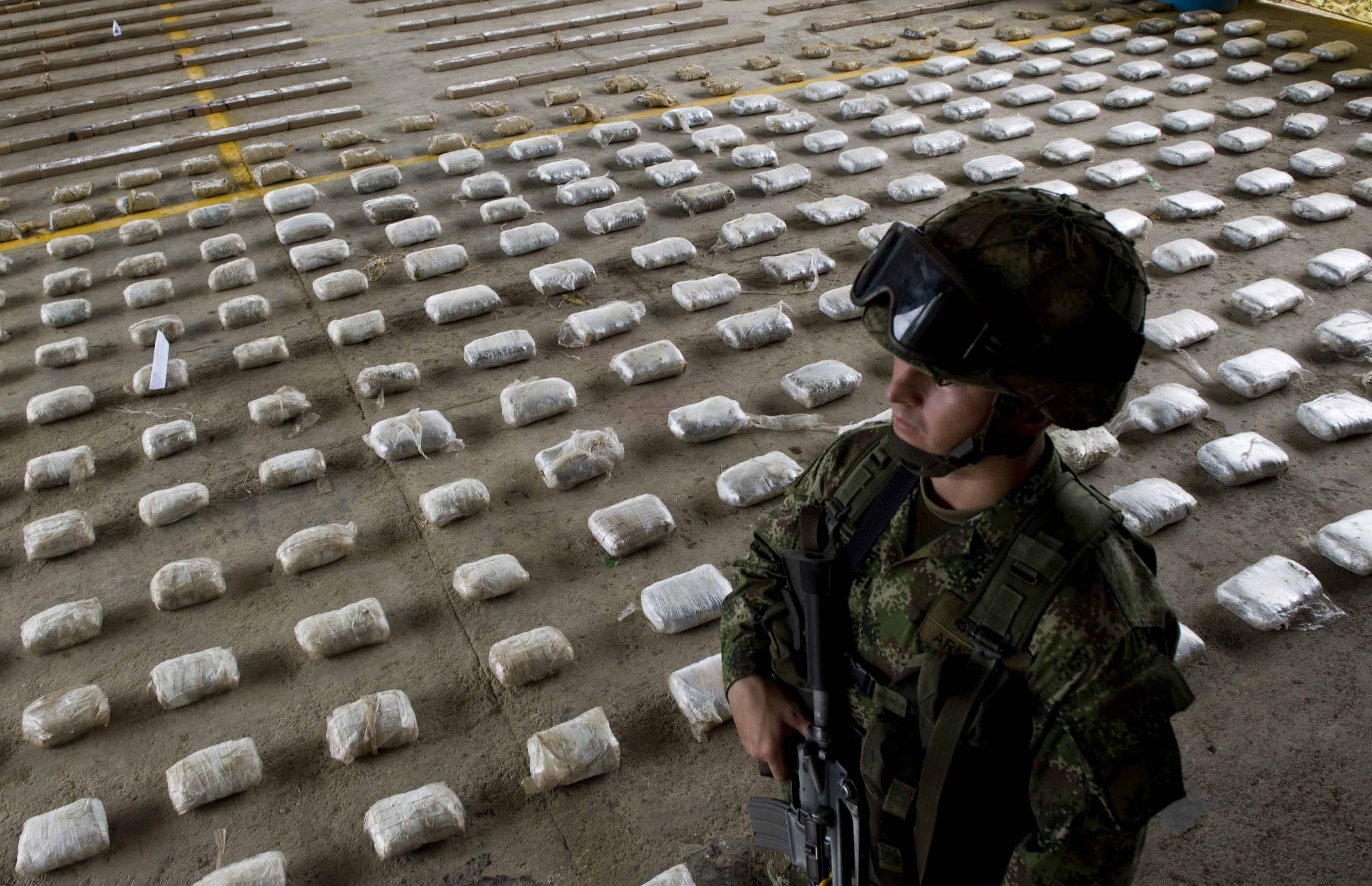 A Colombian soldier stands next to packages of seized cocaine.