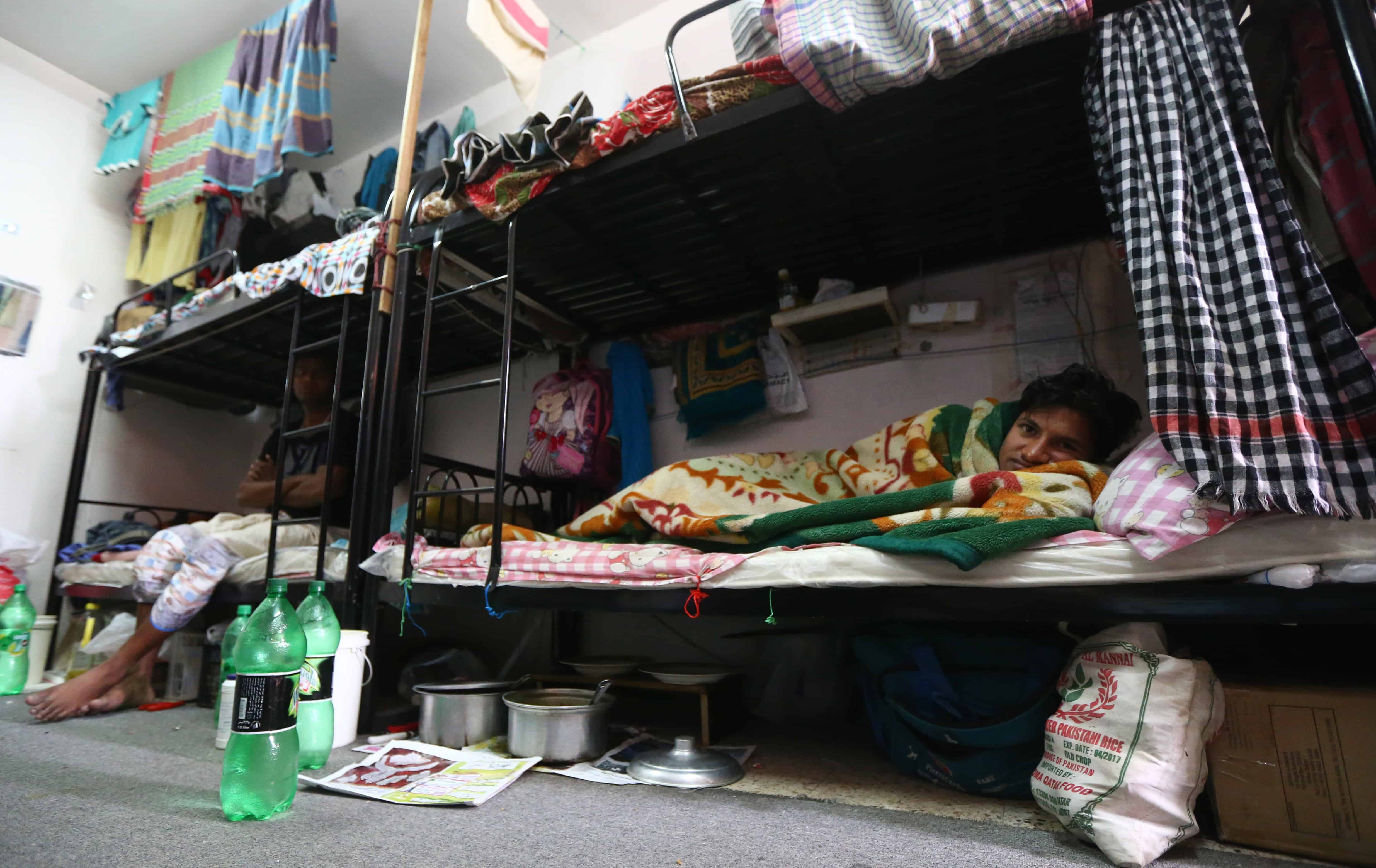 Mubarak, a laborer from Bangladesh, rests in his bedroom at a private camp housing foreign workers in Doha.