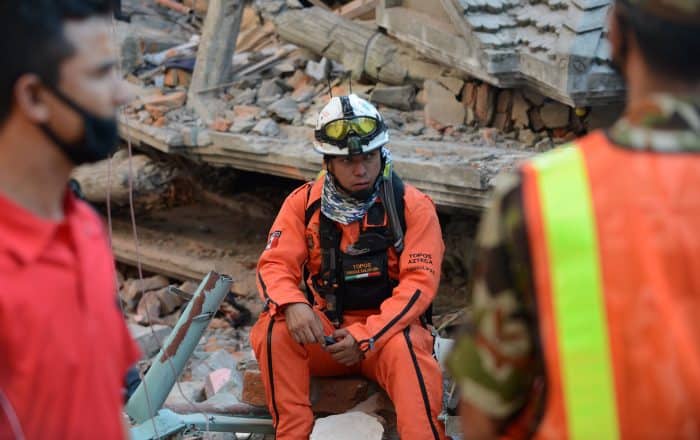 Rescue team officials, including one man from Mexico, center, look on during a search.