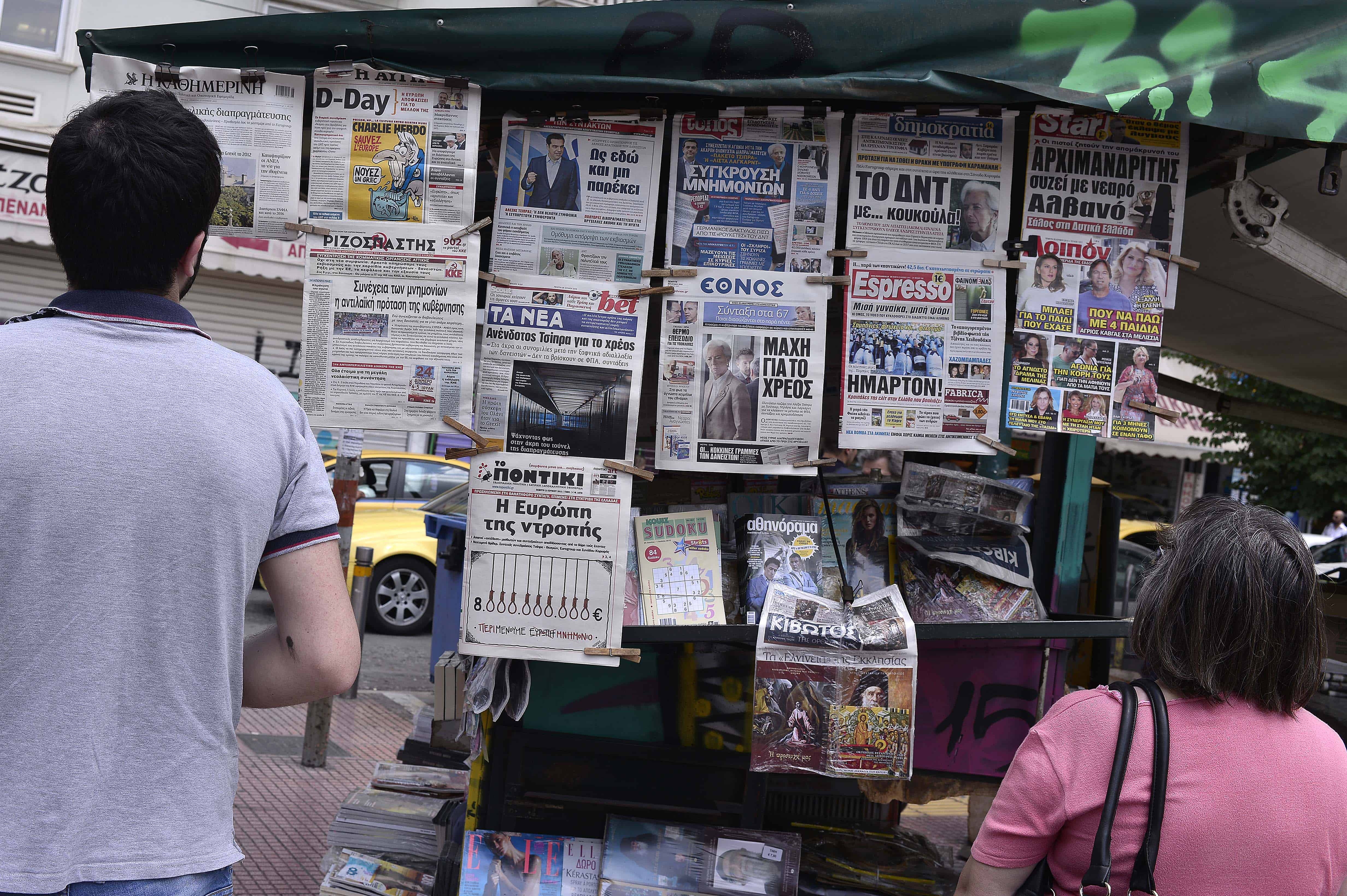 Onlookers view newspaper headlines in central Athens on June 25, 2015.