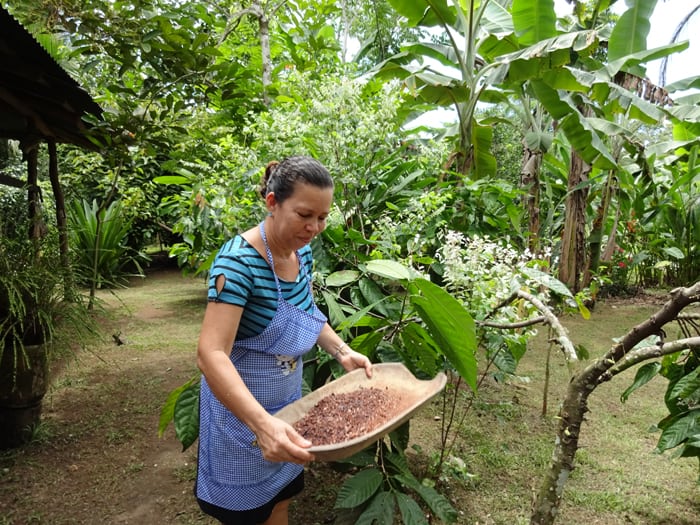 Rosy Quirós shakes crushed cacao beans into the air to make the shells blow away.
