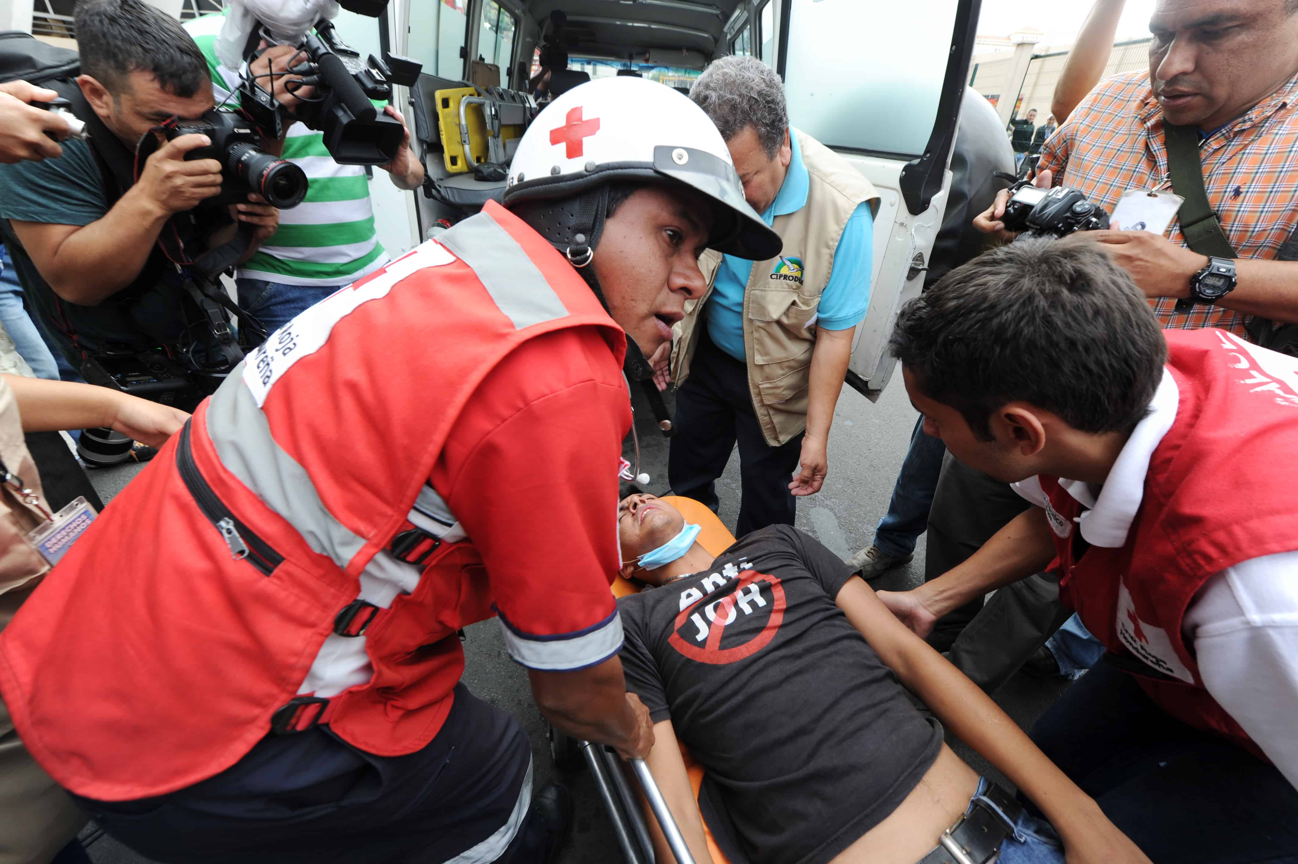 Red Cross members help a protester after he was hurt during clashes with the police in the surroundings of the Presidential Palace in Tegucigalpa, on July 16, 2015. At least 22 people on hunger strike, including Human Rights activist Wilfredo Mendez, demand the installation of an international commission against impunity in Honduras.