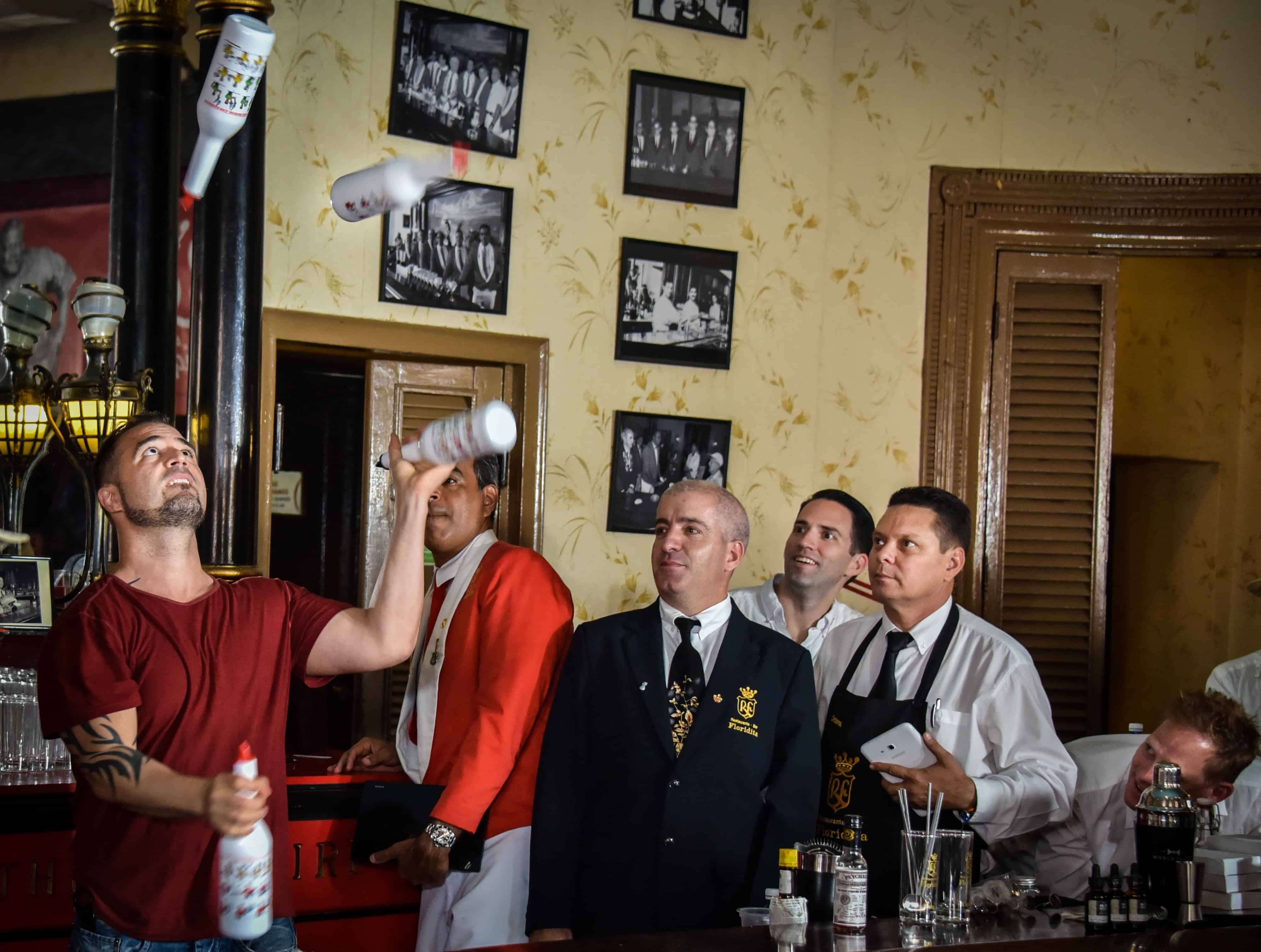 Argentine bartender Christian Delpech (left), who lives and works in Las Vegas, plays with bottles of rum at the Floridita bar in Havana, on July 24, 2015.
