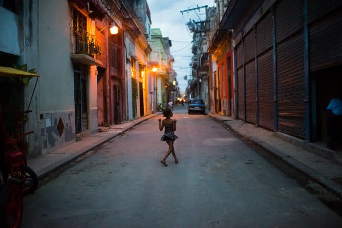 A young girl walks down San Ignacio Street in Old Havana as the sun sets.