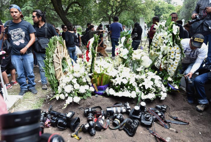 Colleagues of murdered Mexican photographer Rubén Espinosa place their cameras beside his grave .