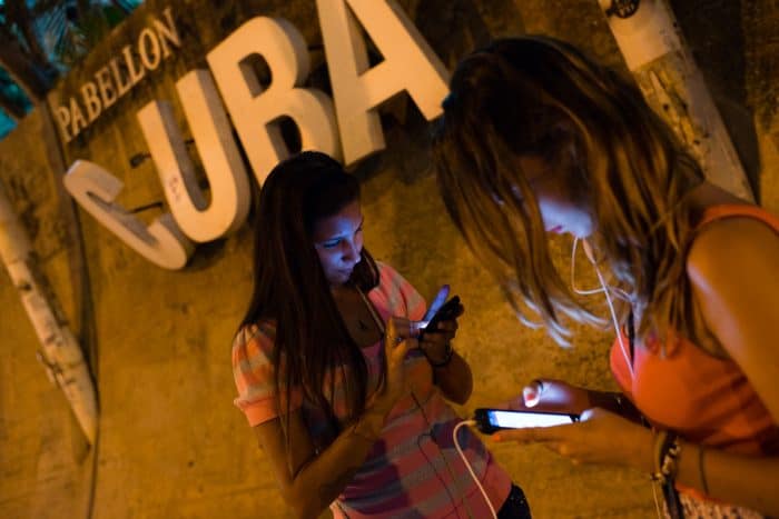 Using a new internet hotspot in Havana, Carolina Baez, 16, left, uses Facebook as her friend, Lara Gonzales, 16, video chats with an aunt in Miami on August 3. The recent addition of public WiFi hotspots has made the internet much more affordable in Cuba.