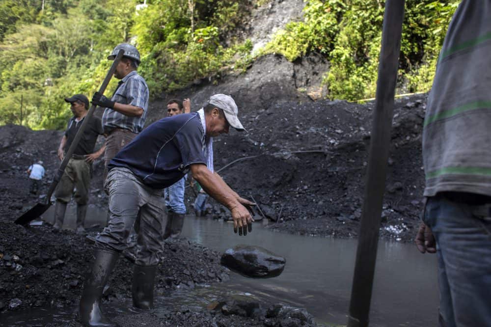 Emerald mine laborer José Vicente Ico, center, drops a rock while digging through mined rubble outside the Minería Texas Colombia plant in Muzo, Colombia, on July 26, 2015. Apart from the rare chance that they strike big, informal emerald miners usually make between $35 and $70 dollars a month.