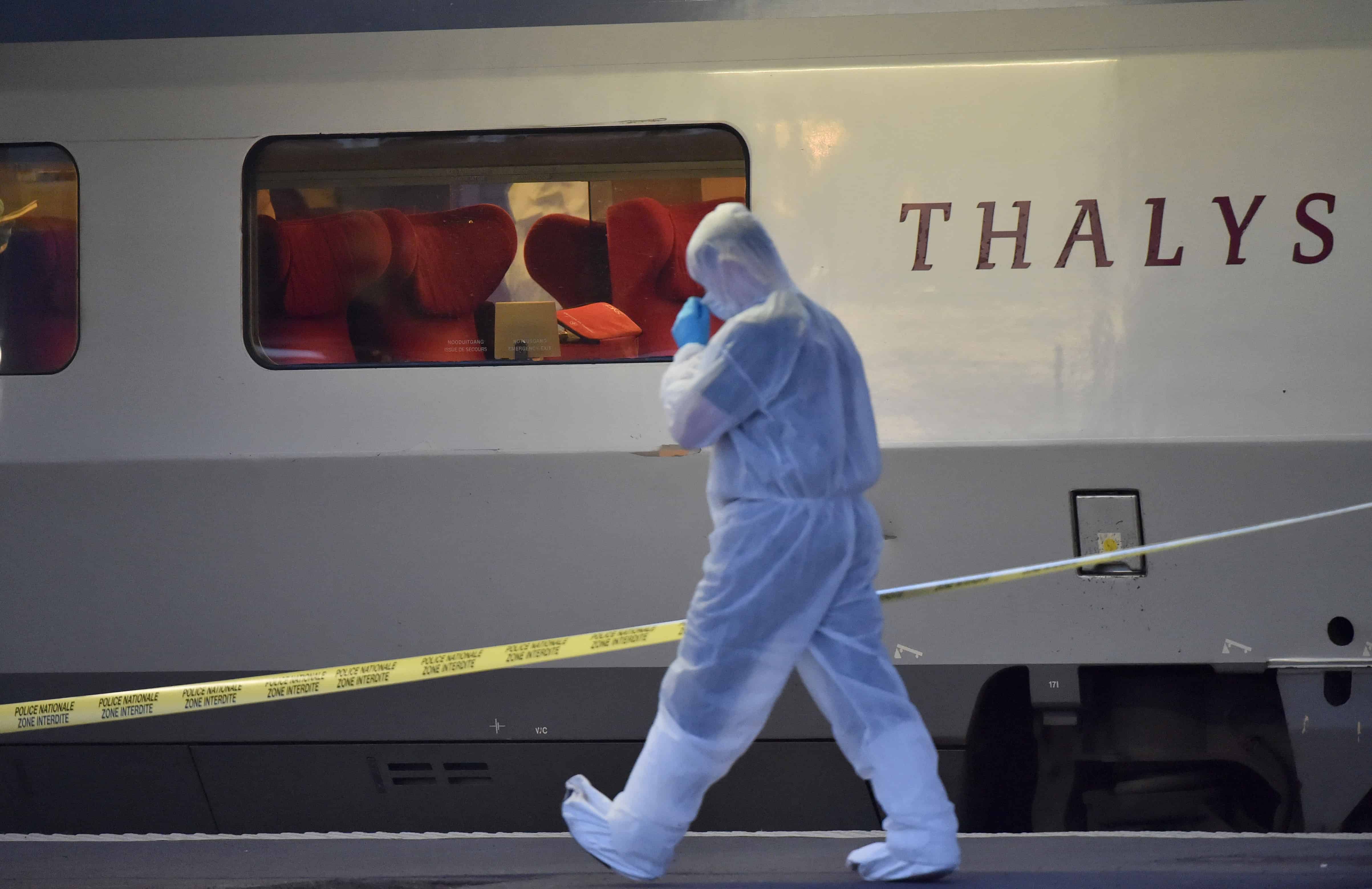 Police officers walk on a platform next to a Thalys train.