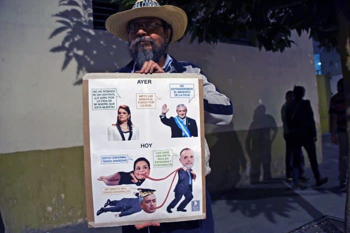 A man holds a sign with pictures of Guatemalan President Otto Pérez Molina, ex-Vice President Roxana Baldetti and the chief of the International Commission Against Impunity in Guatemala, Iván Velásquez. 
