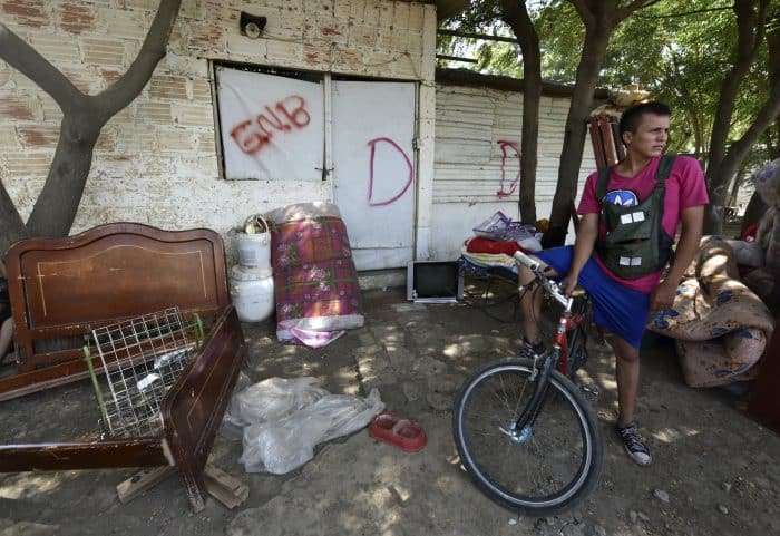 A Colombian who was deported from Venezuela waits in front of his now former house, marked with a "D" for demolition, in San Antonio de Táchira, Venezuela, where he returned for his belongings to carry them across the bordering Táchira River, on Aug. 25, 2015. 