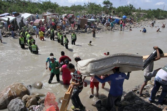 Colombian police help Colombian citizens carry their belongings.