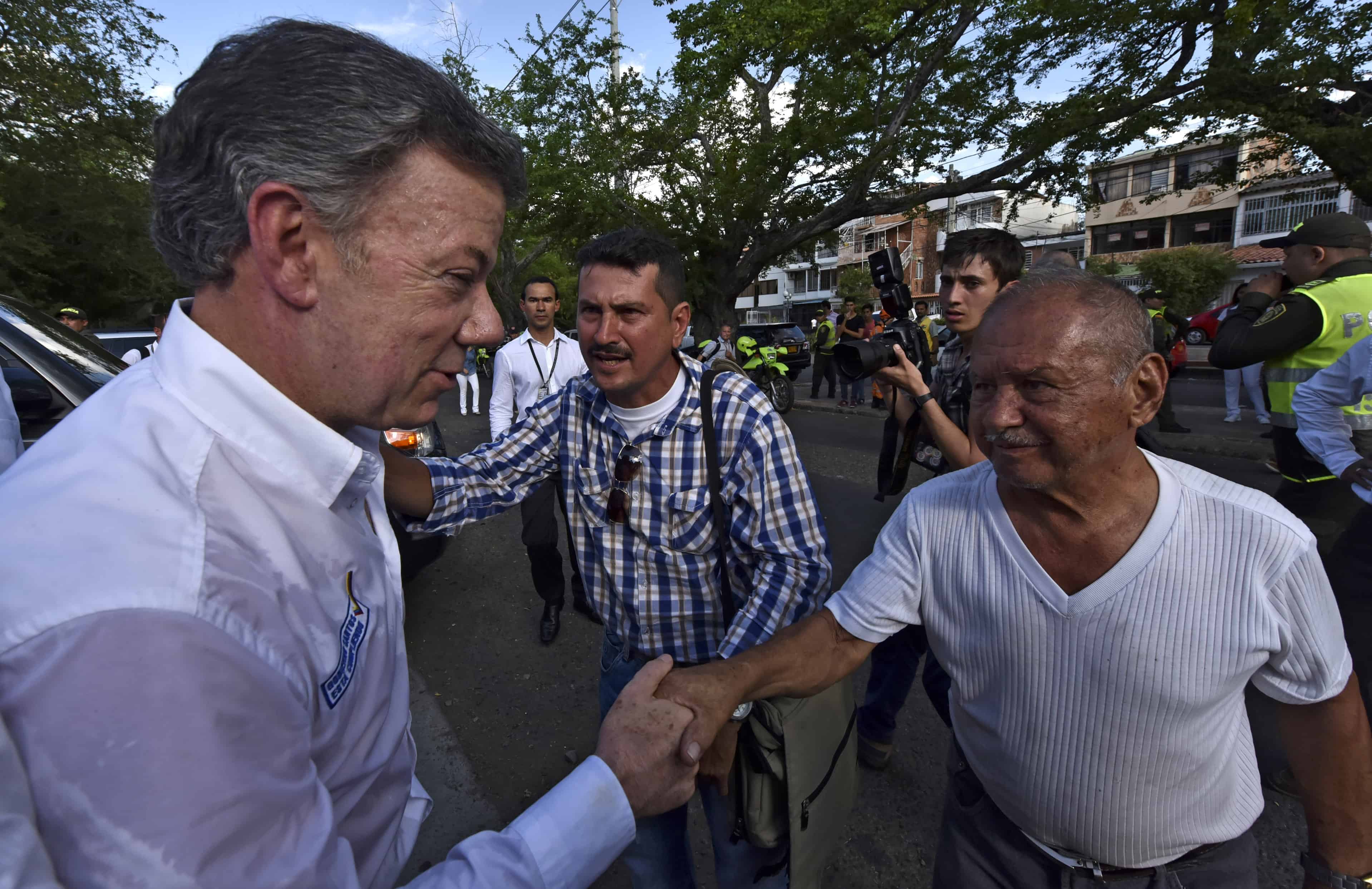 Colombian President Juan Manuel Santos, left, shakes hands with a man during a visit to a shelter in Cucuta, Colombia.
