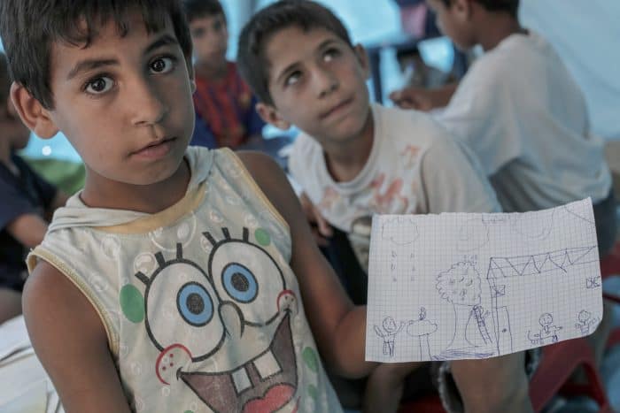 Rashid Hamadi, 9, holds a picture he drew at a school set up by a charity inside a Syrian refugee settlement in Al-Minya, Lebanon.