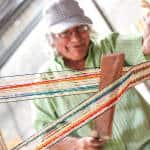Don Tina operates the loom to create a cabuya purse.