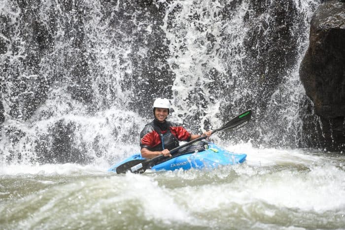 A kayaker at the base of a waterfall.