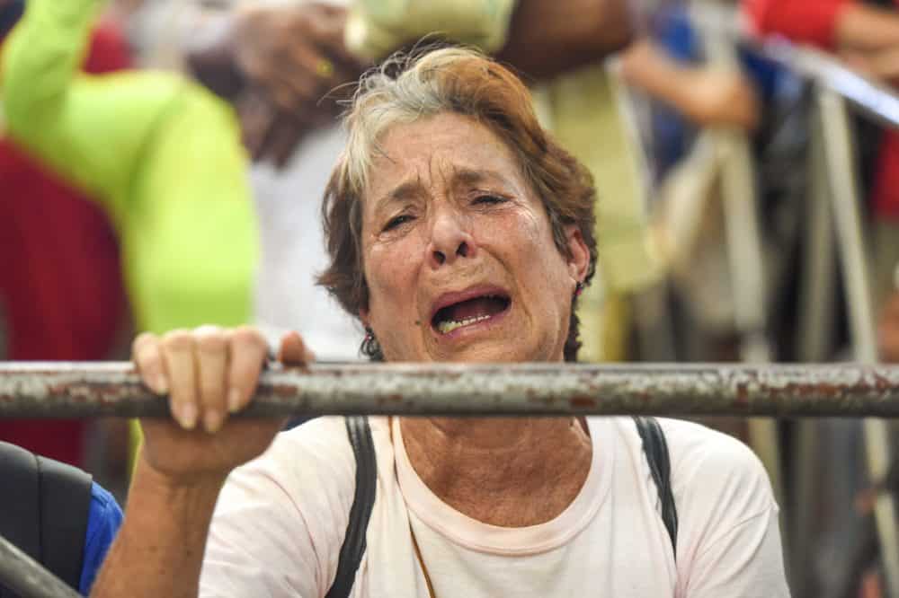 A pilgrim prays to La Negrita to cure a sick family member during the Romería, A