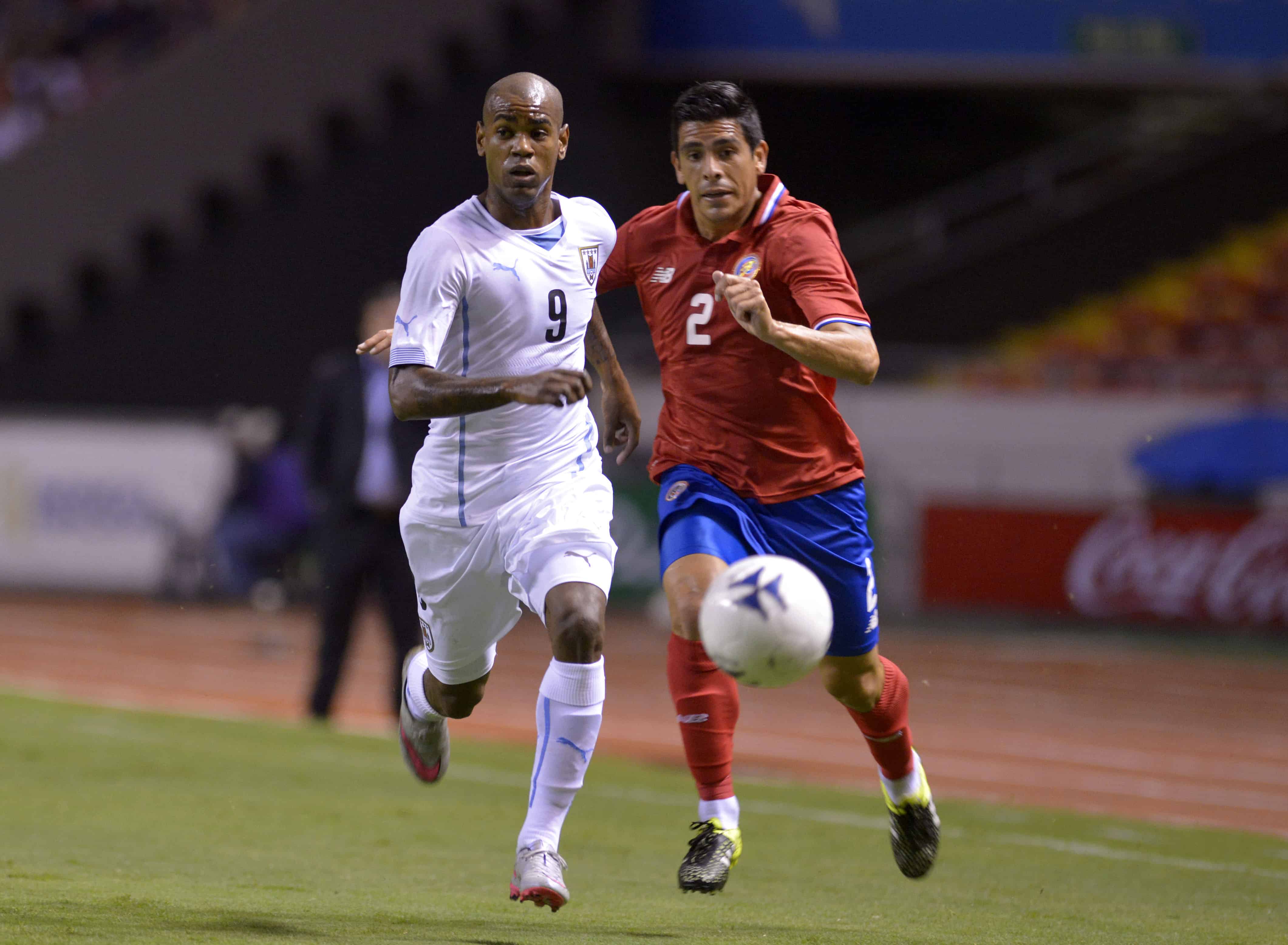 Costa Rica's Johnny Acosta (R) races for the ball with Diego Rolan (L) of Uruguay during La Sele's 1-0 win at the National Stadium in San Jose, Costa Rica, on Sept. 8, 2015.