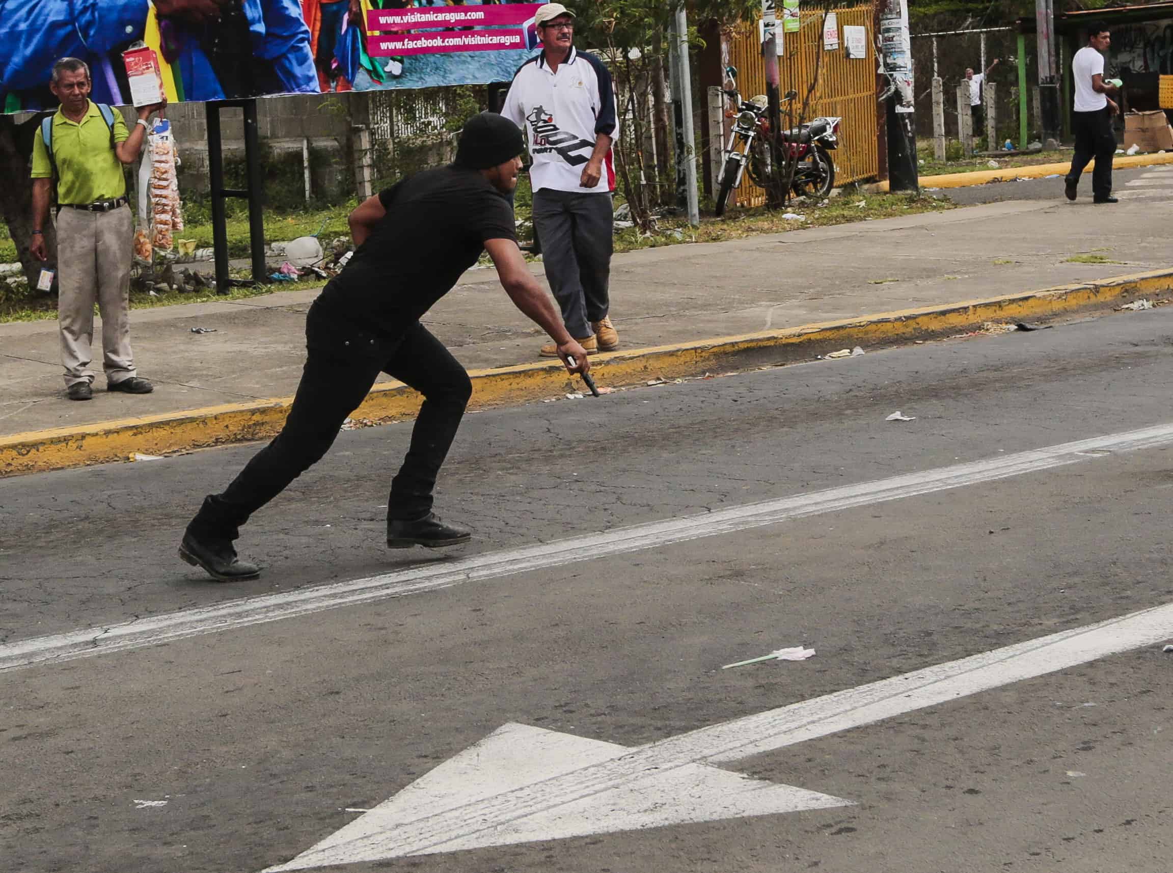 A Sandinista supporter runs with a pistol when chasing opposition members during a protest against the electoral system in Nicaragua, in Managua, on Sept. 2, 2015.