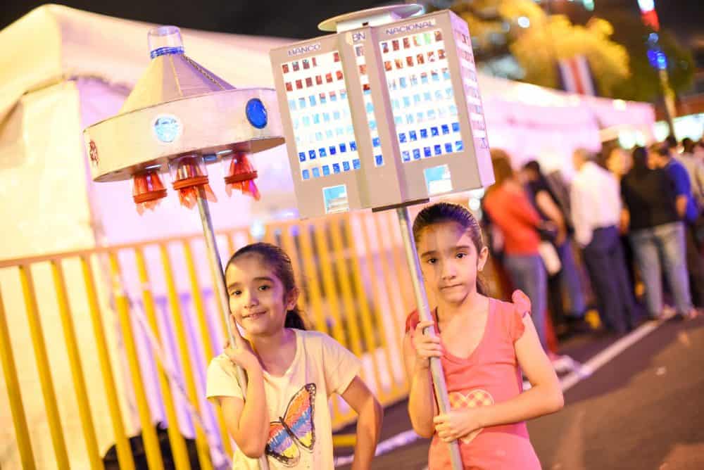 A couple of children holding colorful, handmade lanterns during the desfile de faroles, a traditional lantern parade in Costa Rica's Independence Day celebrations.