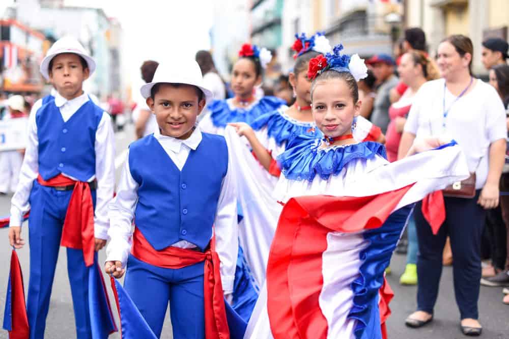 Traditional dancers twirling in vibrant dresses during the Costa Rican Independence Day parade.