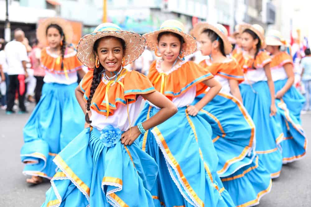 A group of students in traditional dress performing a cultural dance during the Independence Day parade.