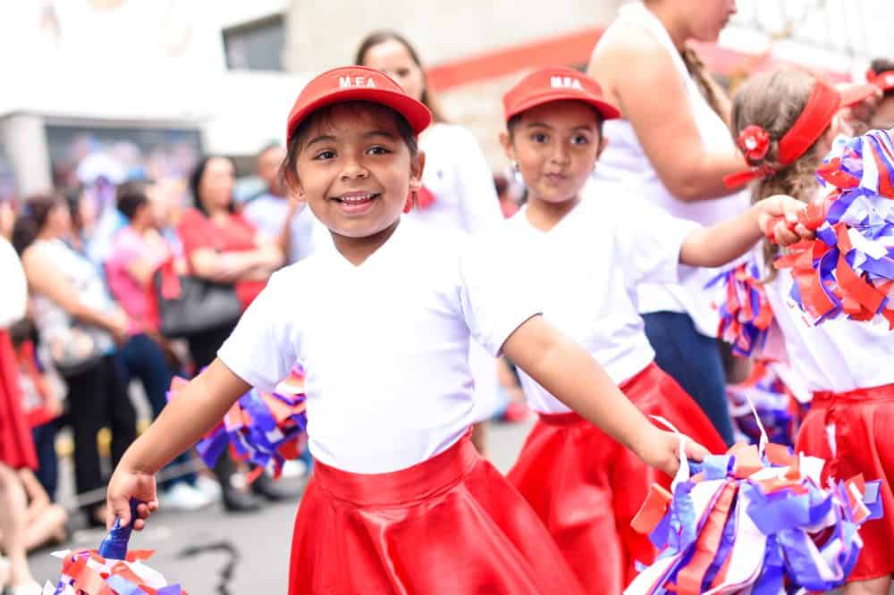 schoolchildren carrying Costa Rican flags in a patriotic display during the parade