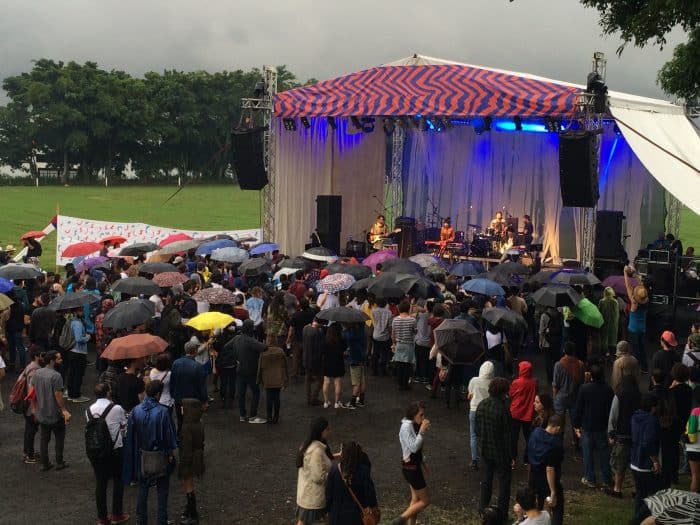 An umbrella audience enjoying Buscabulla's performance. Elizabeth Lang/ The Tico Times