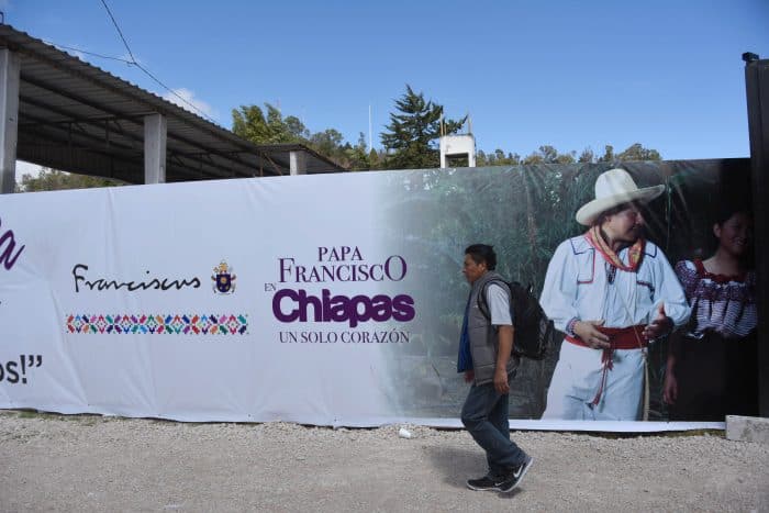 A man passes a banner welcoming Pope Francis near where he will officiate an open-air mass in San Cristobal de las Casas, Chiapas State, Mexico