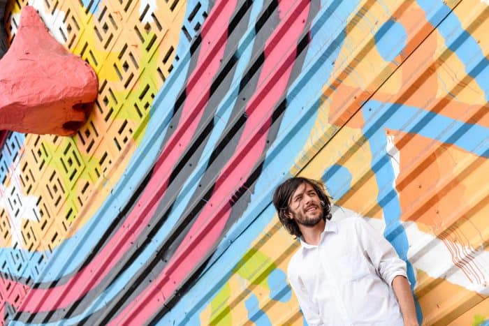 Gussa posing next to his artwork.