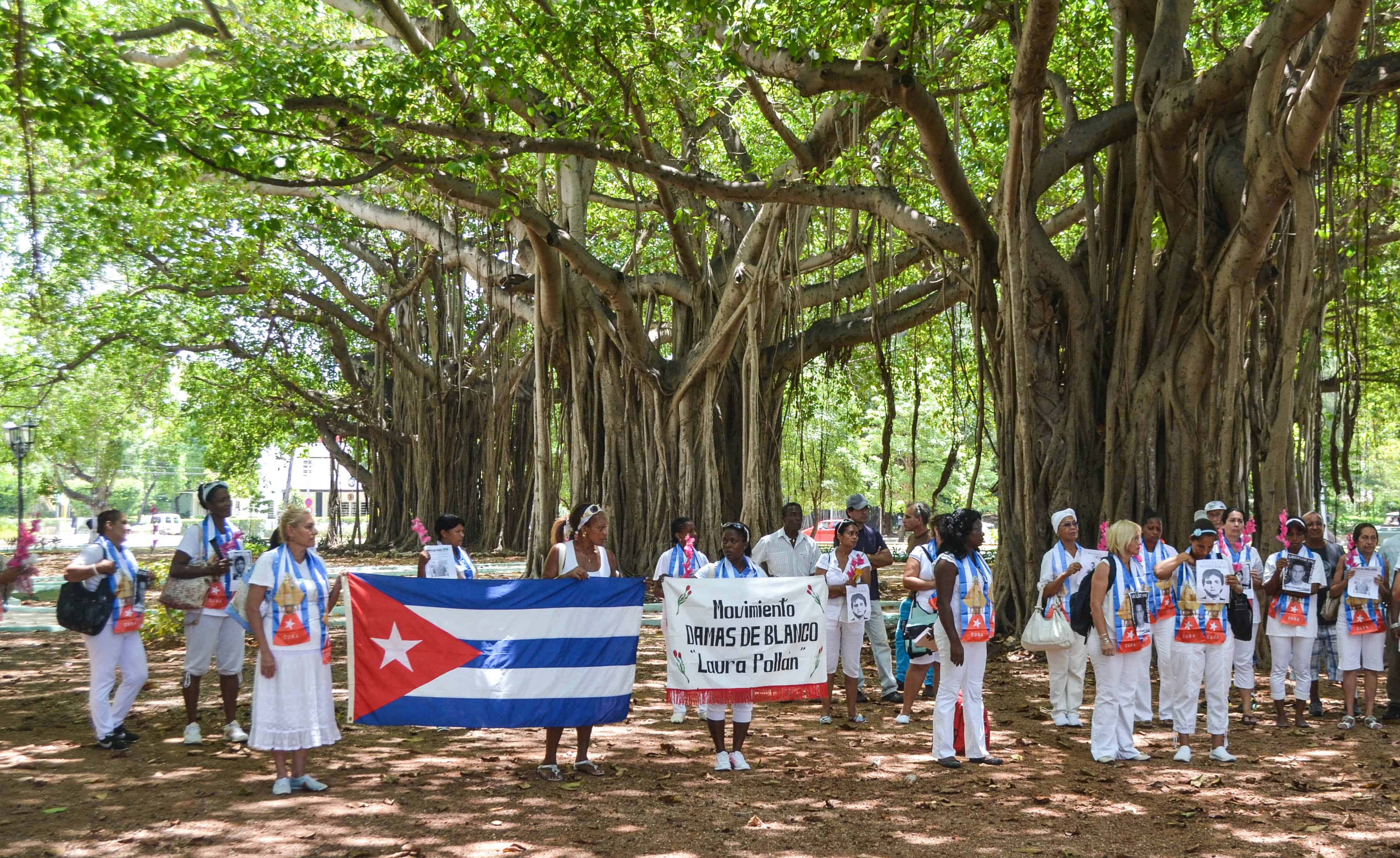 Cuban dissidents and members of the Ladies in White human rights group hold a Cuban national flag and pictures of imprisoned dissidents.