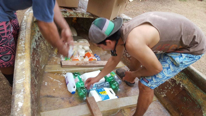 Alberto Robleto Jr. places empty plastic bottles in the bottom of the boat.