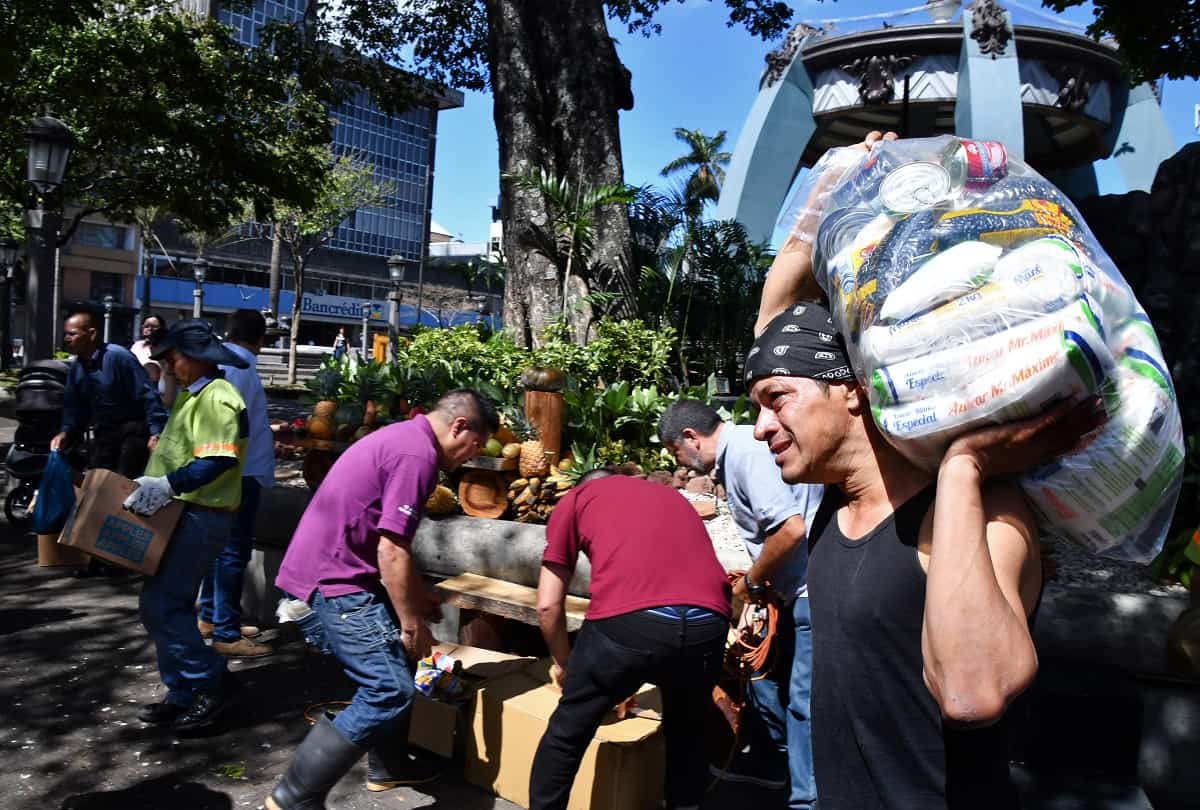 People arrange agricultural products donated for people in need as part of a Holy Week event at San José, Costa Rica's Central Park on March 28, 2018.