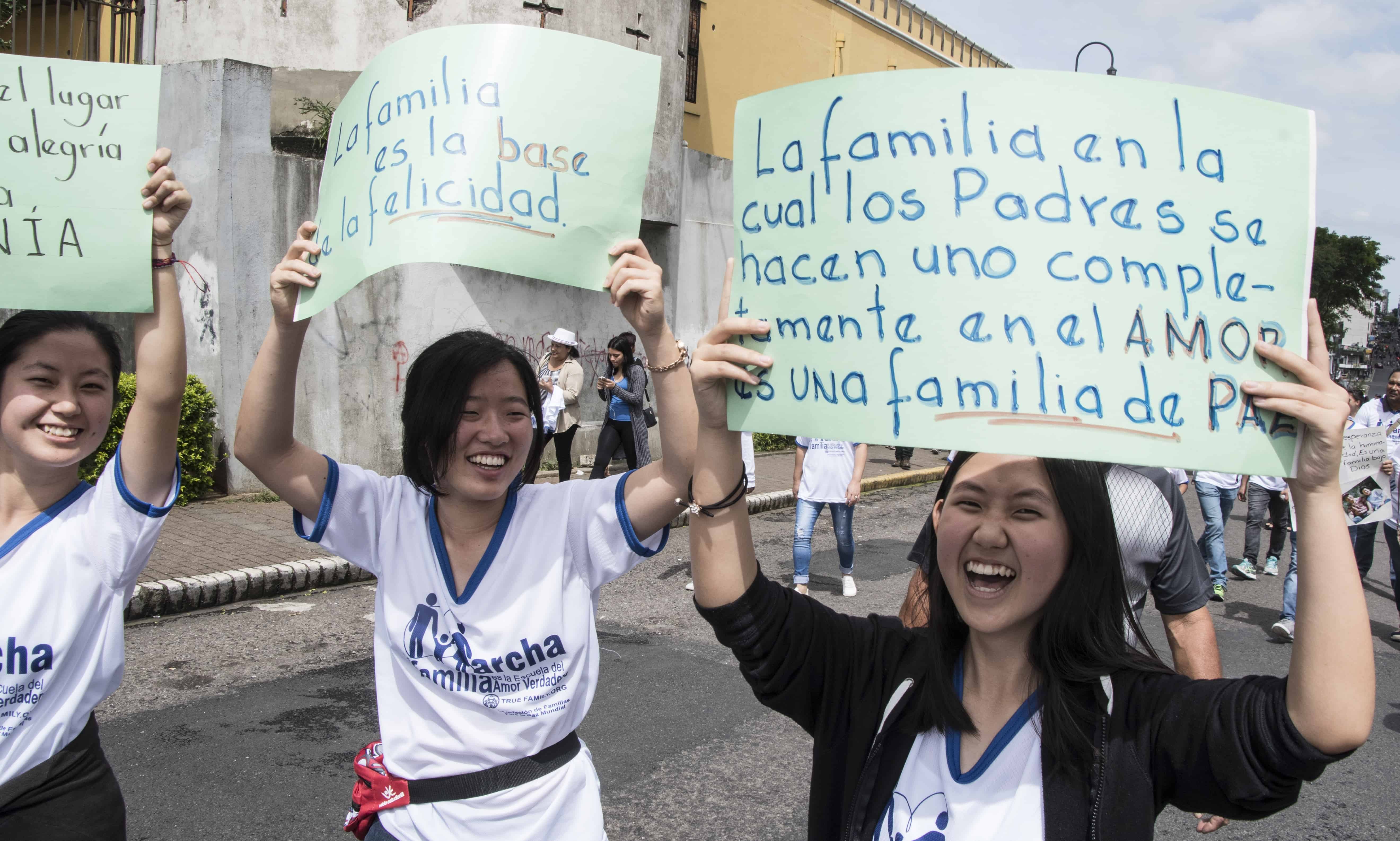 Women hold signs in favor of the traditional family during a march in San José, on July 15, 2018.